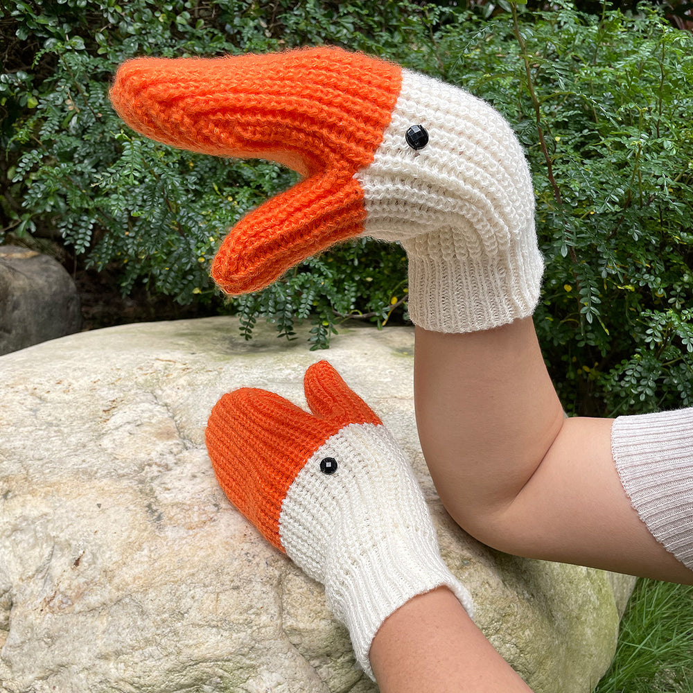 Knitted white goose mittens with orange beaks