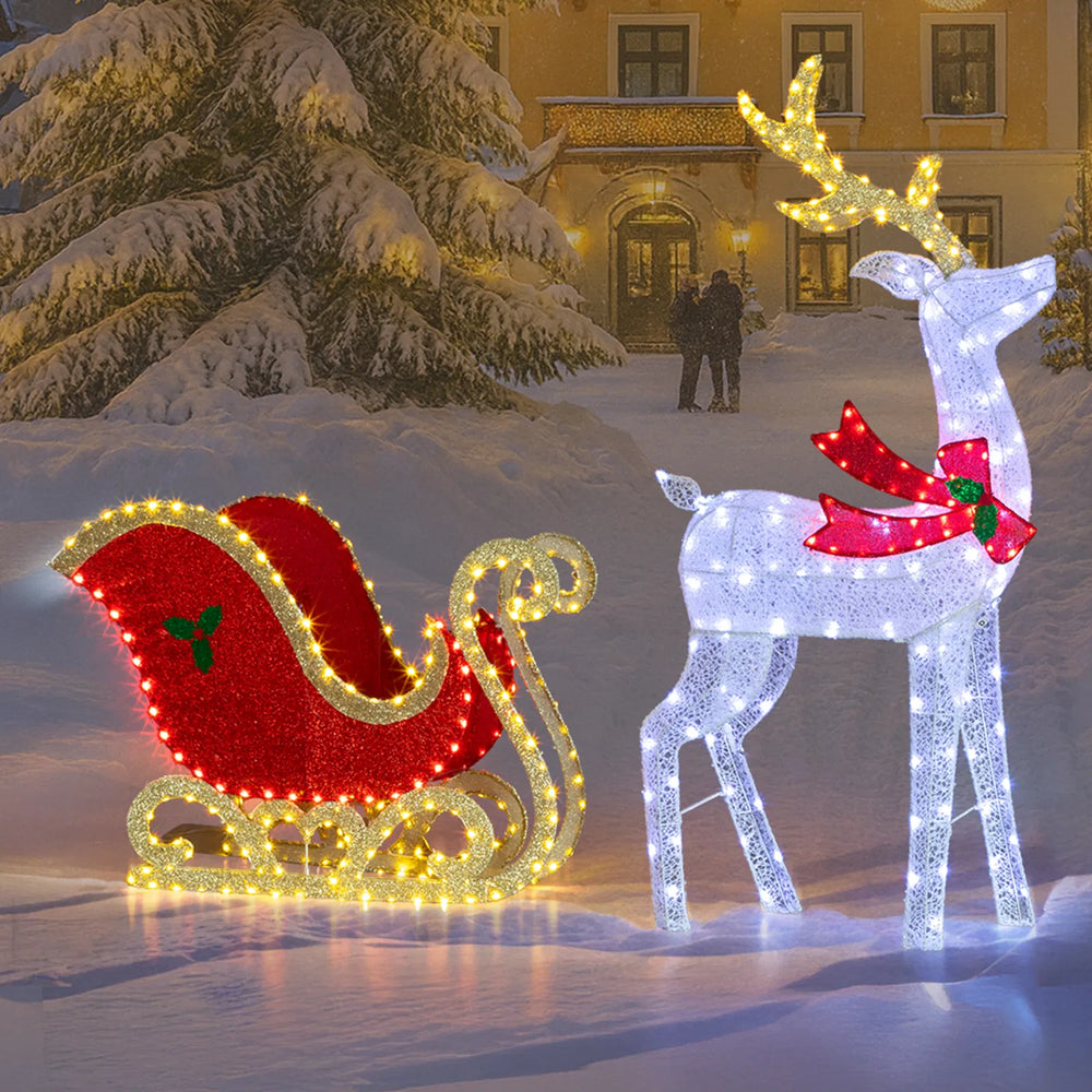 Lighted reindeer and sleigh at night