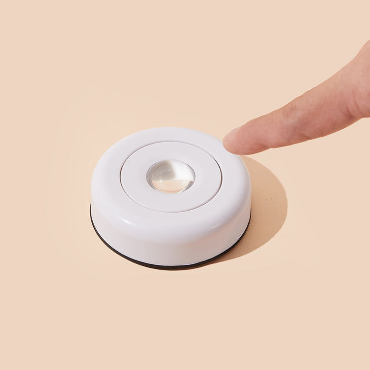Stick-on push light glowing on a wall